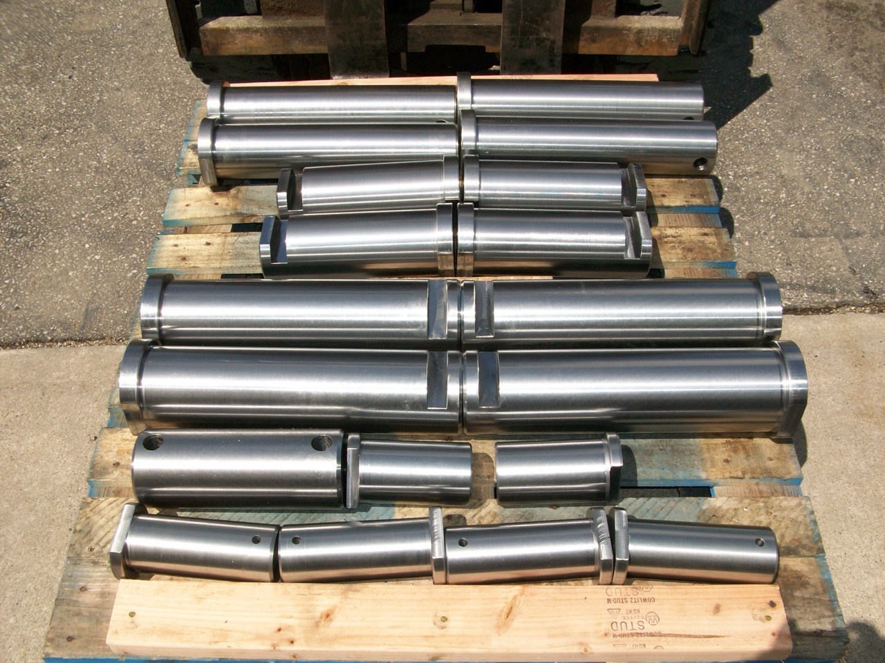 Finished set of precision-machined dredge bucket pins on a pallet